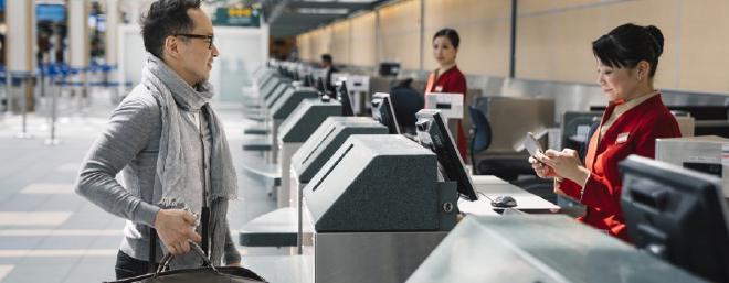 Man loading luggage onto conveyer belt.